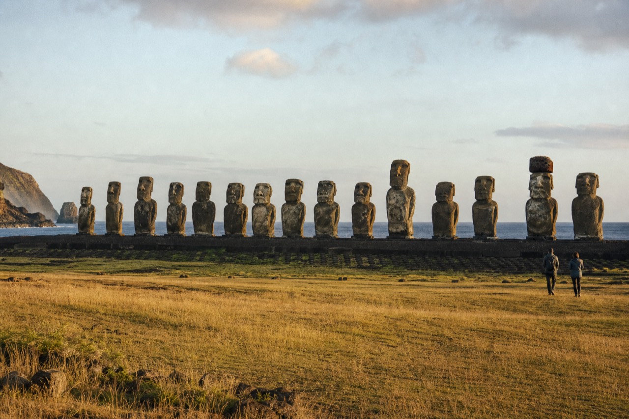 Fifteen moai standing shoulder to shoulder on the long ahu at Tongariki with open Pacific water behind them in low morning light