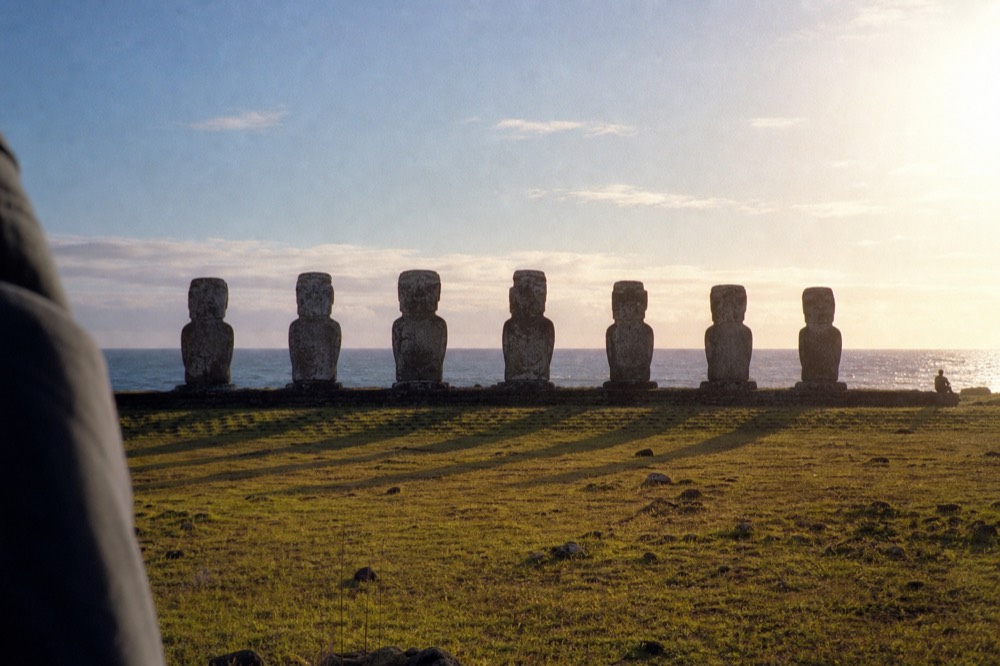 Seven moai of Ahu Akivi standing in a line on open grassland facing away from the inland hills