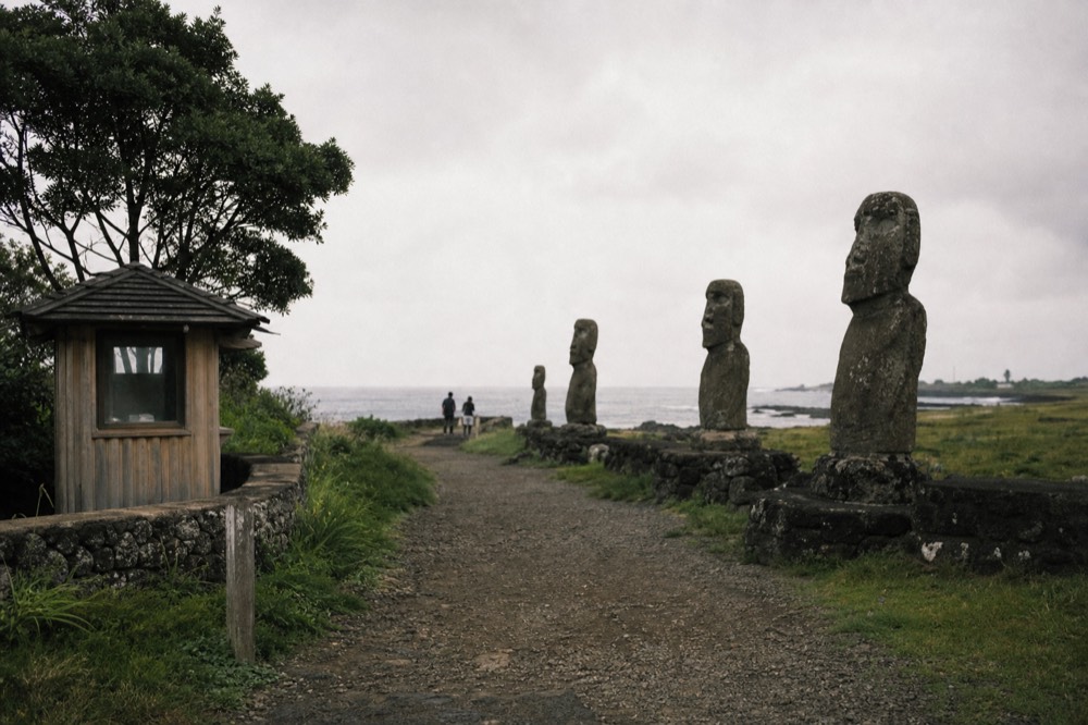 Small wooden ranger booth at a park site entrance with a gravel path leading toward the coast